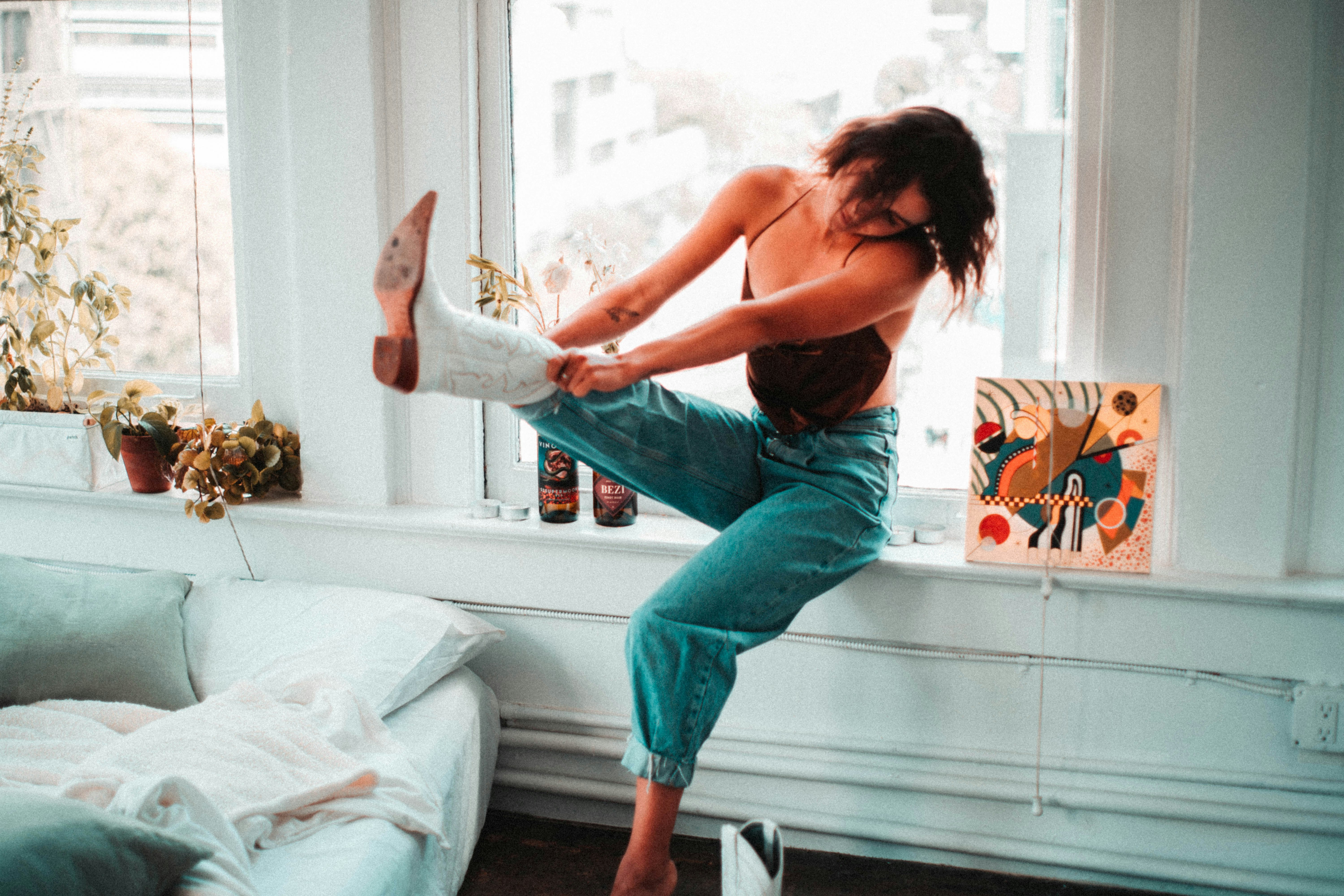 woman in black tank top and blue denim jeans sitting on white wooden table